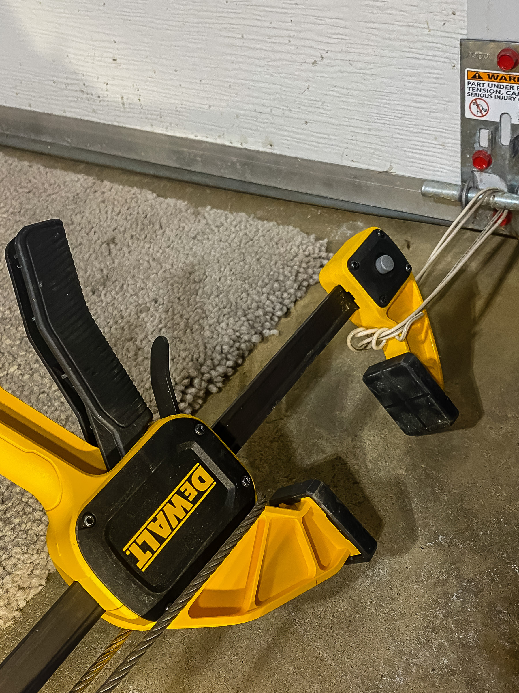 I made a double loop of #14 wire around the bottom of my garage door and a Dewalt bar clamp. Keep the tie point low.