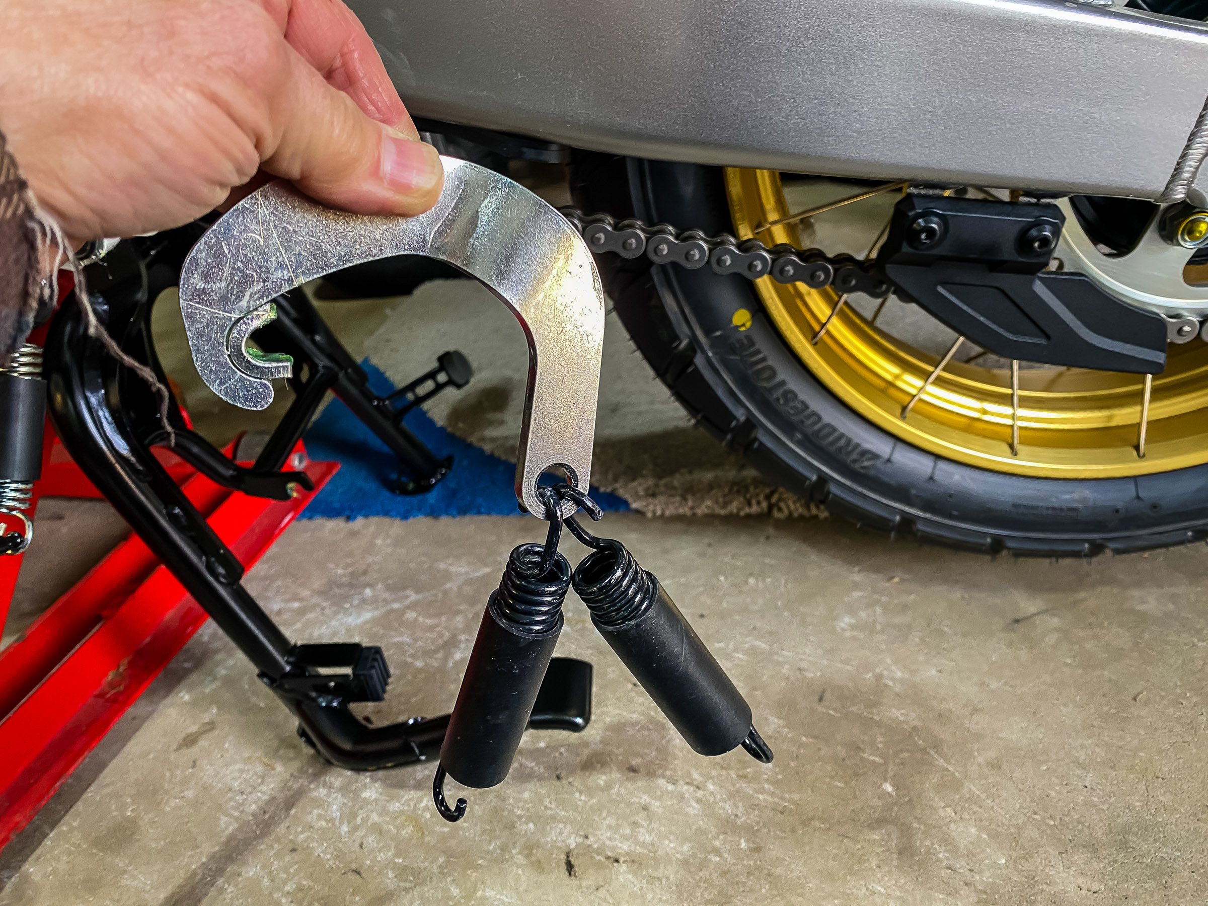 Prep the tensioner hook by putting grease in the 'C' area and attaching the springs, each going through the hole in the opposite direction.