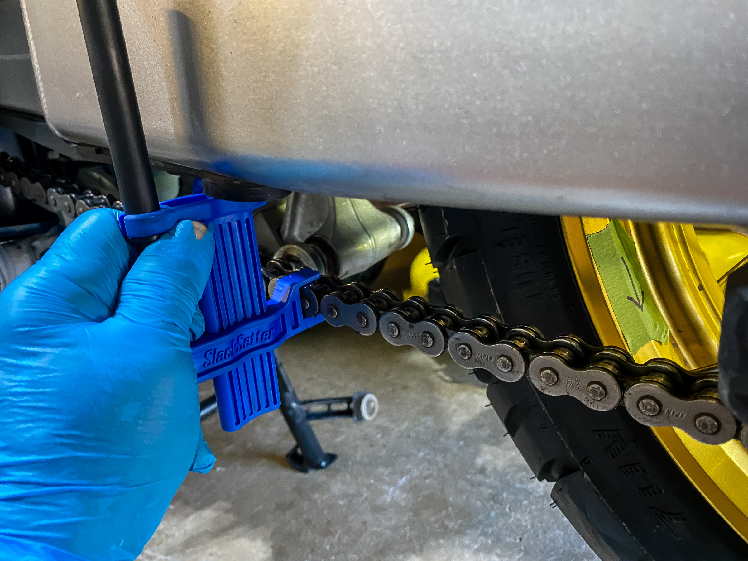 Turn the wheel clockwise so the chain slack is at the bottom. Put the slacksetter tool under the swing arm. and measure the slack. It should be 45 to 50mm. You can measure this with a ruler if you don't have this tool.