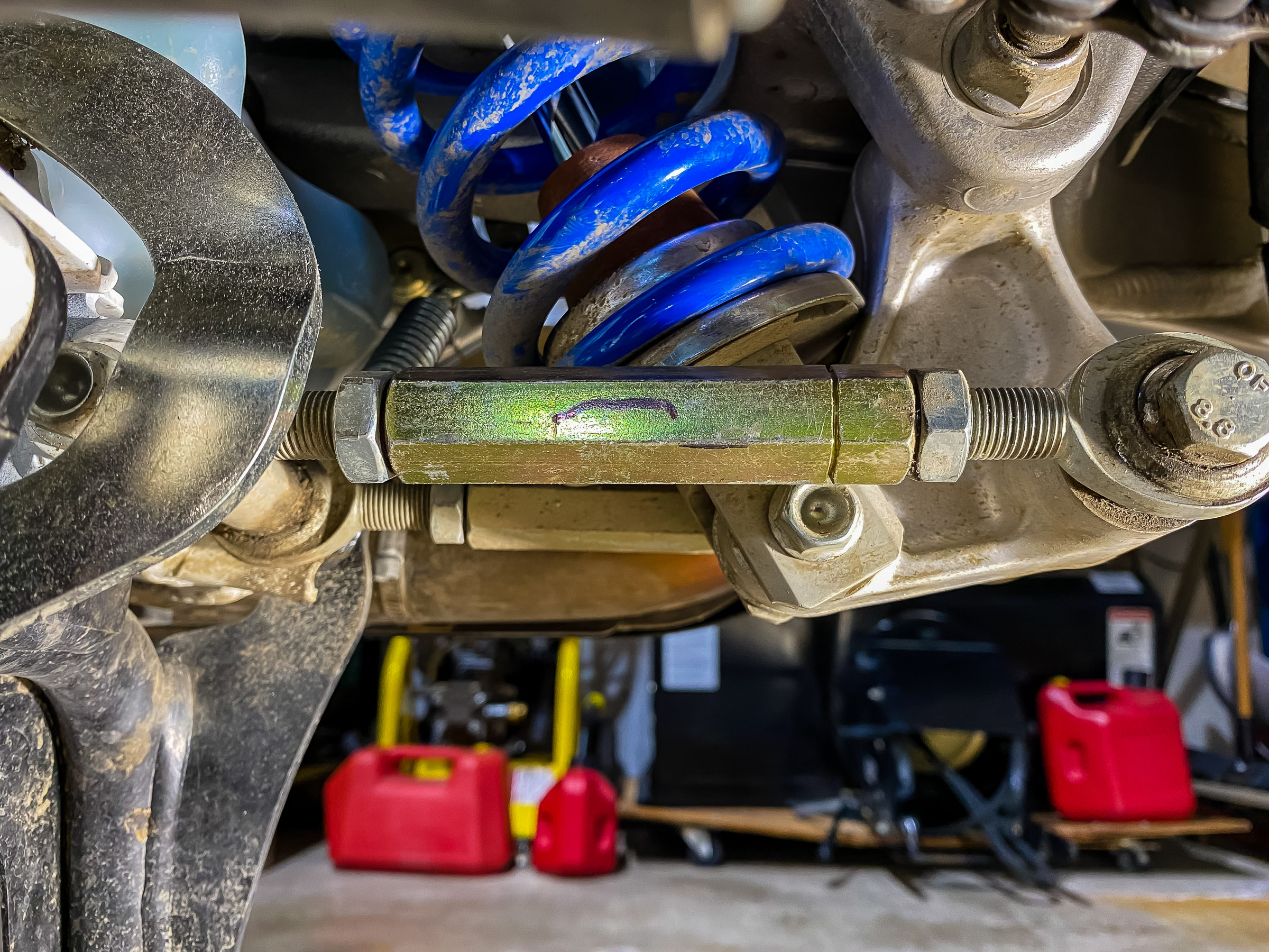 We're looking at the left side  of the bike. The long gold colored hex and the jam nuts are  19mm/ 3/4". I marked the flat of the long hex on its outside face. Loosen the jam nut on  the right which is a left hand thread indicated by the groove cut in the gold hex.. The  jam nut on the left is a standard right hand thread. To lower the bike you have  to make the link longer. Put a 19mm / 3/4" wrench on the long hex and push it down. Count the number of flats you turn it. Do the same on the other side. Both sides have to be equal.