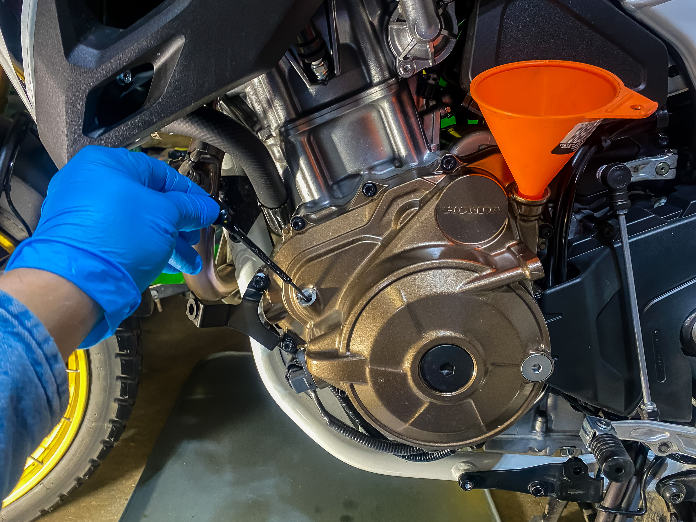 With the bike straight up stick the dip  stick in the hole. Don't screw it in. Fill the bike till the oil is at the top mark on the dipstick. Run the bike for a few minutes. Check for oil leaks. Replace the skid plate