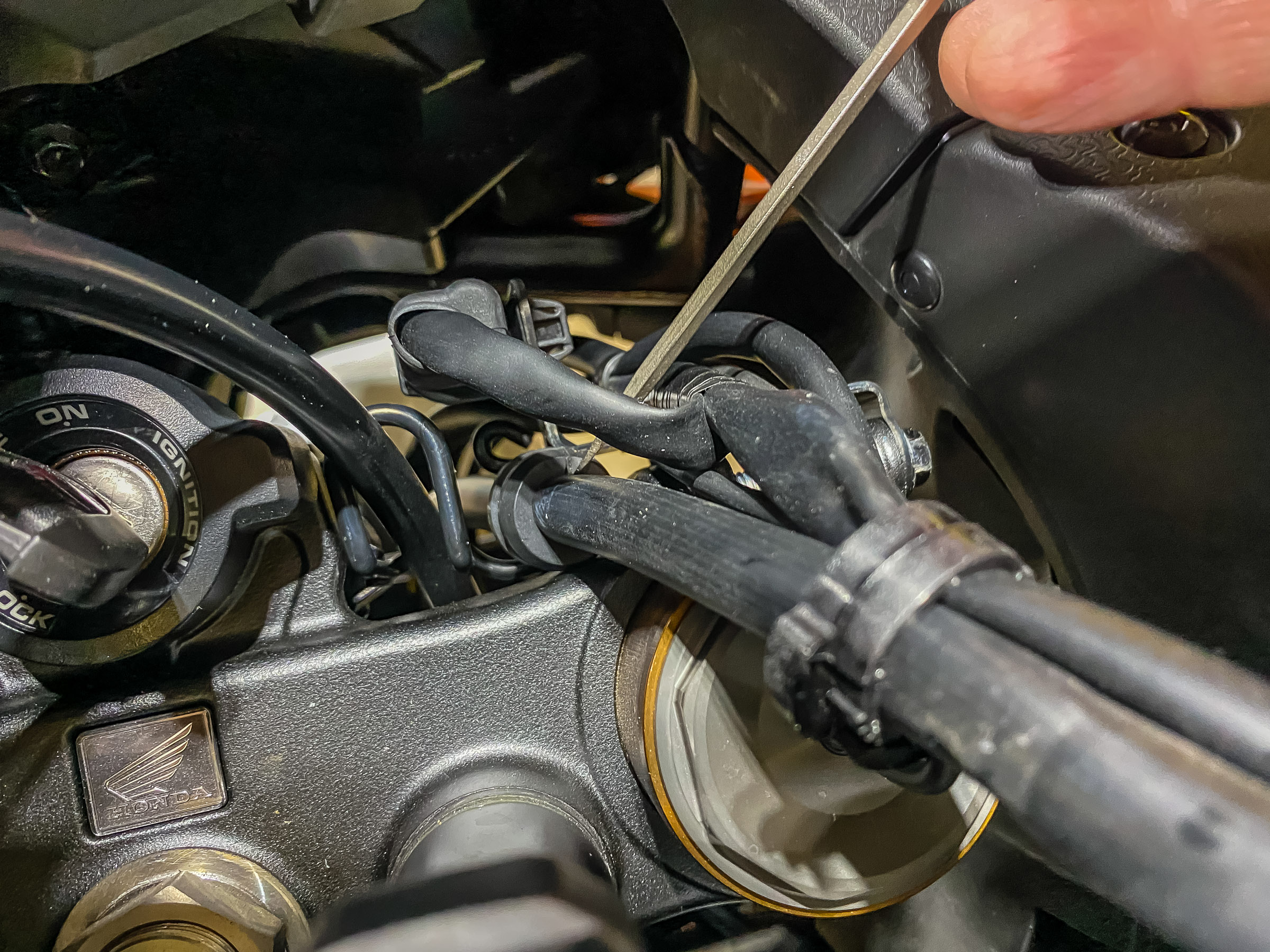 Pushing the brake line grommet out of the retainer clip with a screwdriver.